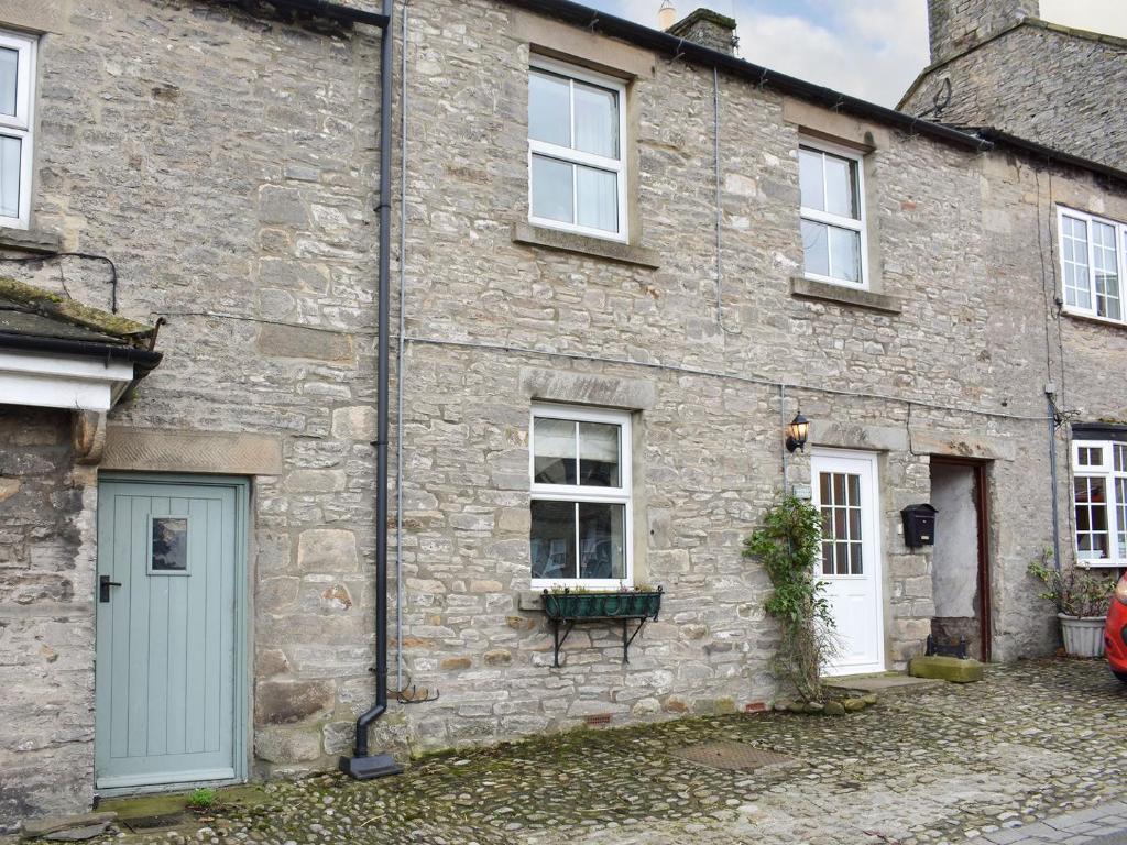 uma casa de pedra com uma porta azul e janelas em Slaters Cottage em Middleham