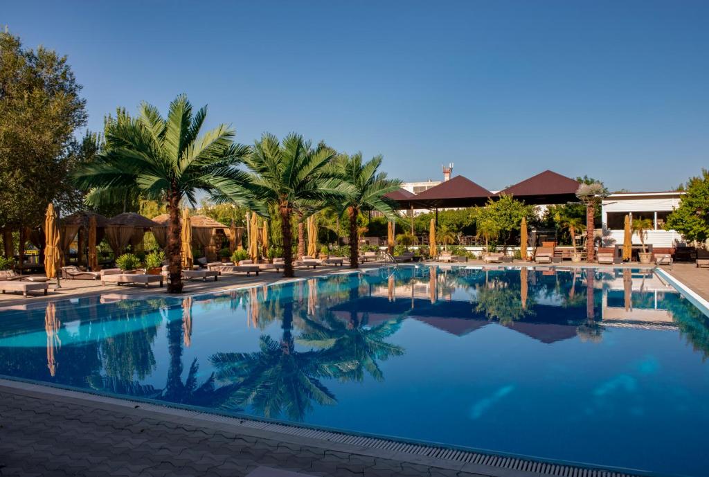 a pool at a resort with palm trees and chairs at Cross Resort Hotel in Yerevan