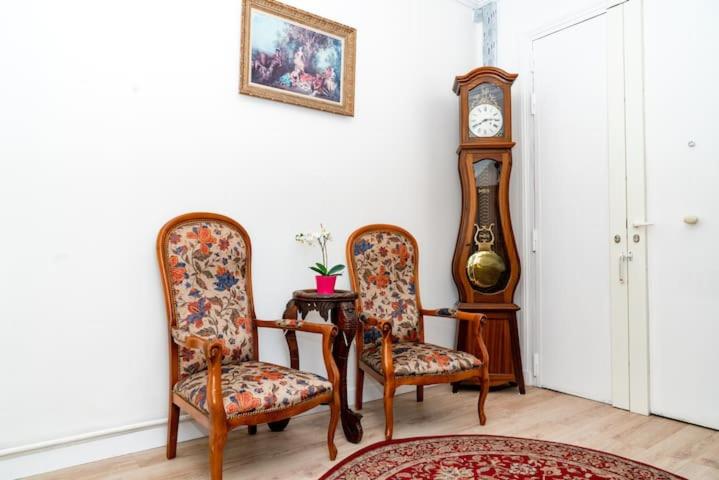 a room with two chairs and a grandfather clock at Appartement de charme avec vue sur place de la République in Paris