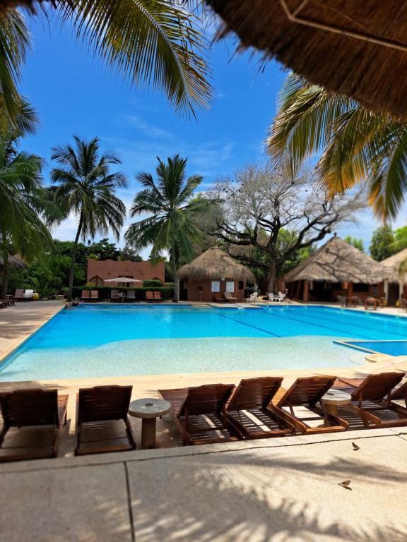 a large swimming pool with chairs and palm trees at Neptune in Saly Portudal