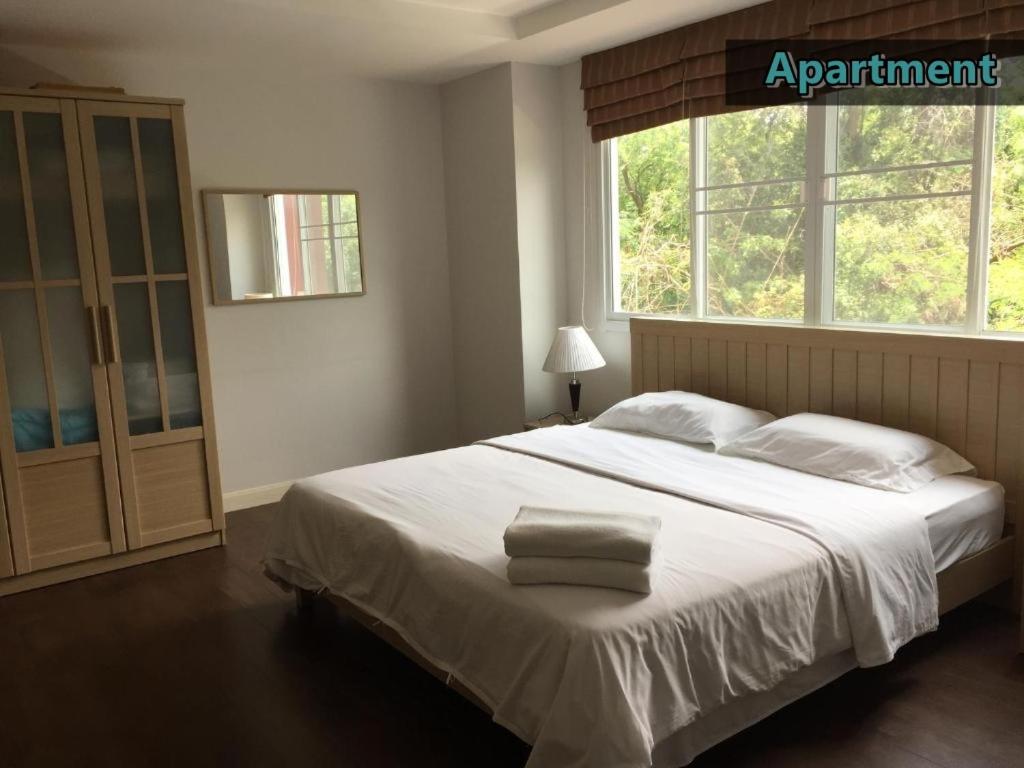 1 dormitorio con 1 cama blanca grande y ventana en Jomtien Beach Penthouses Condo en Jomtien Beach