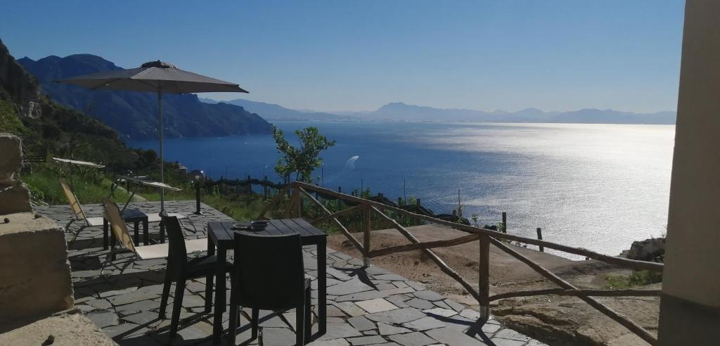 una mesa con sillas y una sombrilla junto al agua en Le Finestre di Amalfi, en Amalfi