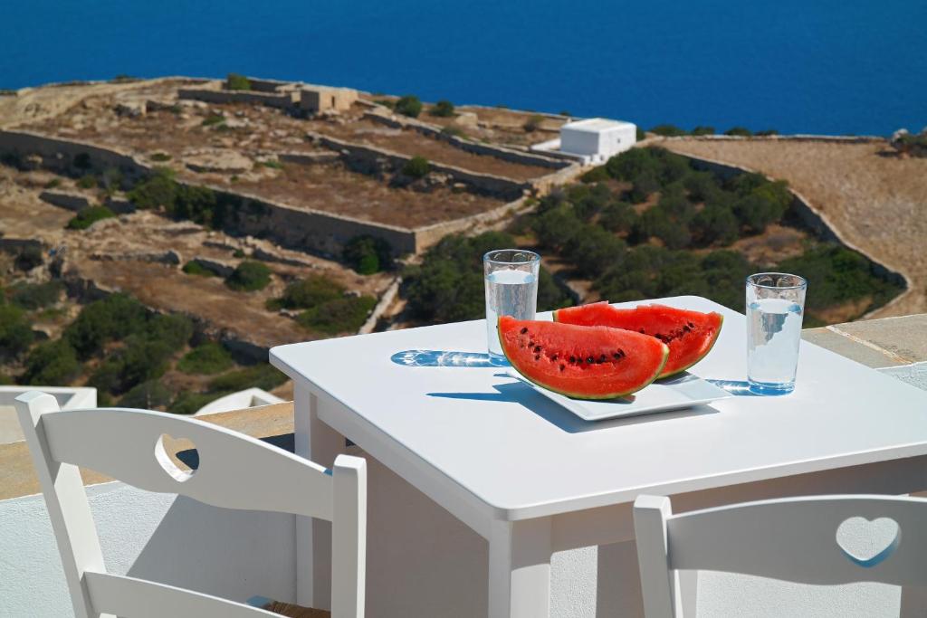 a table with a bowl of watermelon and two glasses at Belvedere Apartments in Chora Folegandros