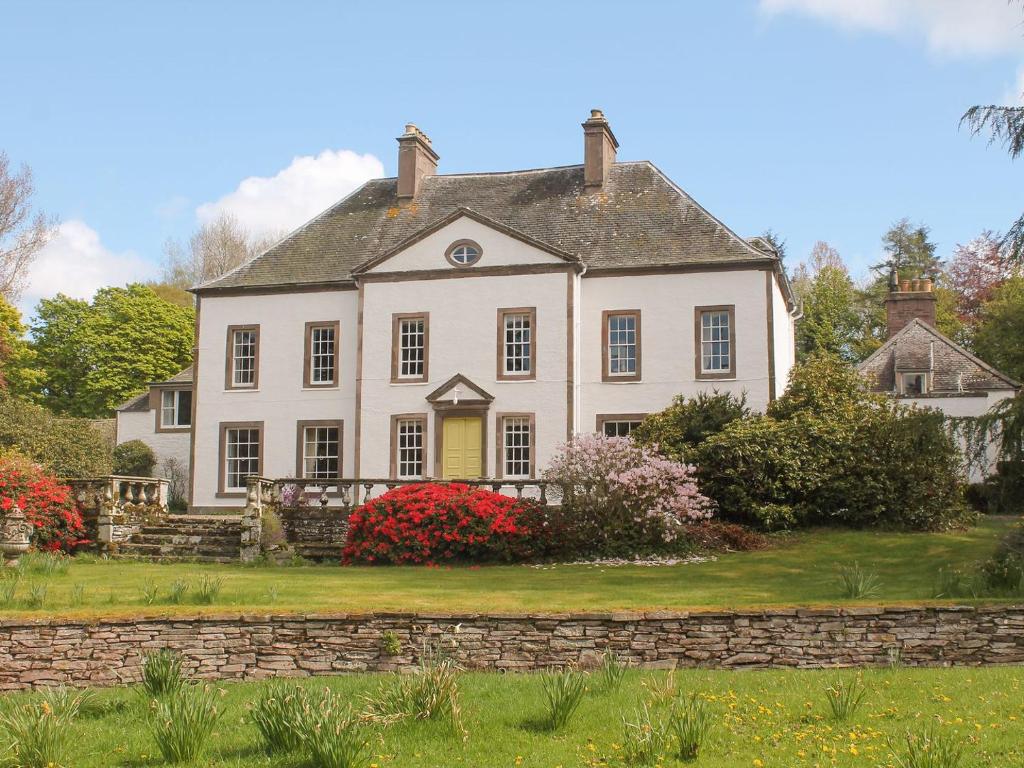 a large white house with a stone wall at The Courtyard Suite in Oathlaw