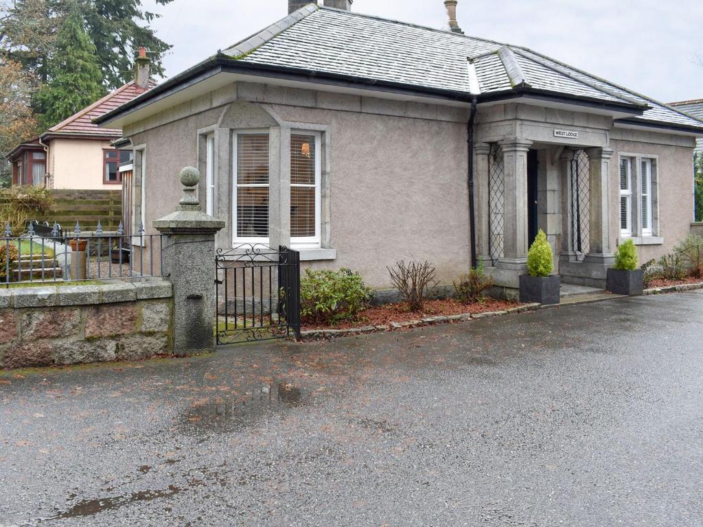 ein Haus mit einem Tor davor in der Unterkunft West Lodge in Banchory