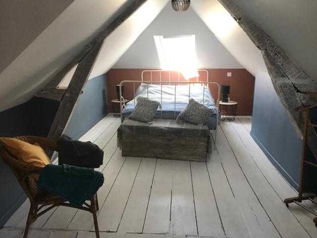 a attic room with a bed and a chair at Niarnia in Abbeville