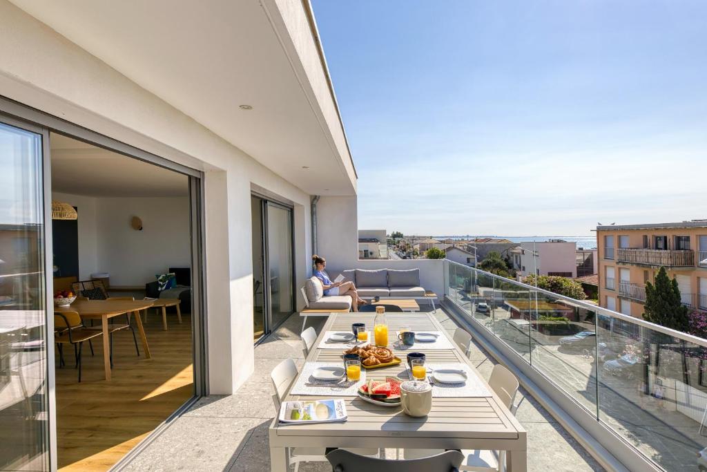 - un balcon avec une table et de la nourriture dans l'établissement SOUTH-OF-FRANCE Magnifique T5 avec CLIM, terrasse 30 m2 vue sur mer et barbecue, parking, 40m de la plage, à Carnon-Plage