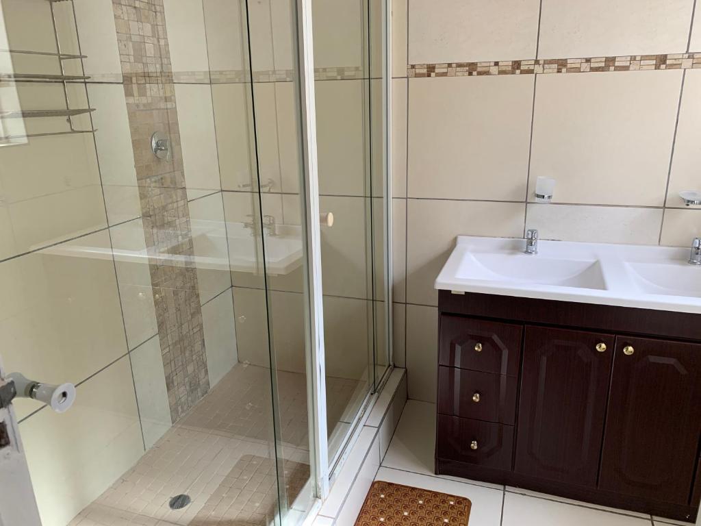 uma casa de banho com um chuveiro e um lavatório. em Esperamos em Durban