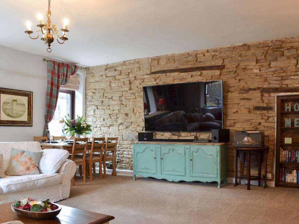 a living room with a tv on a brick wall at Cross Cottage in Haworth