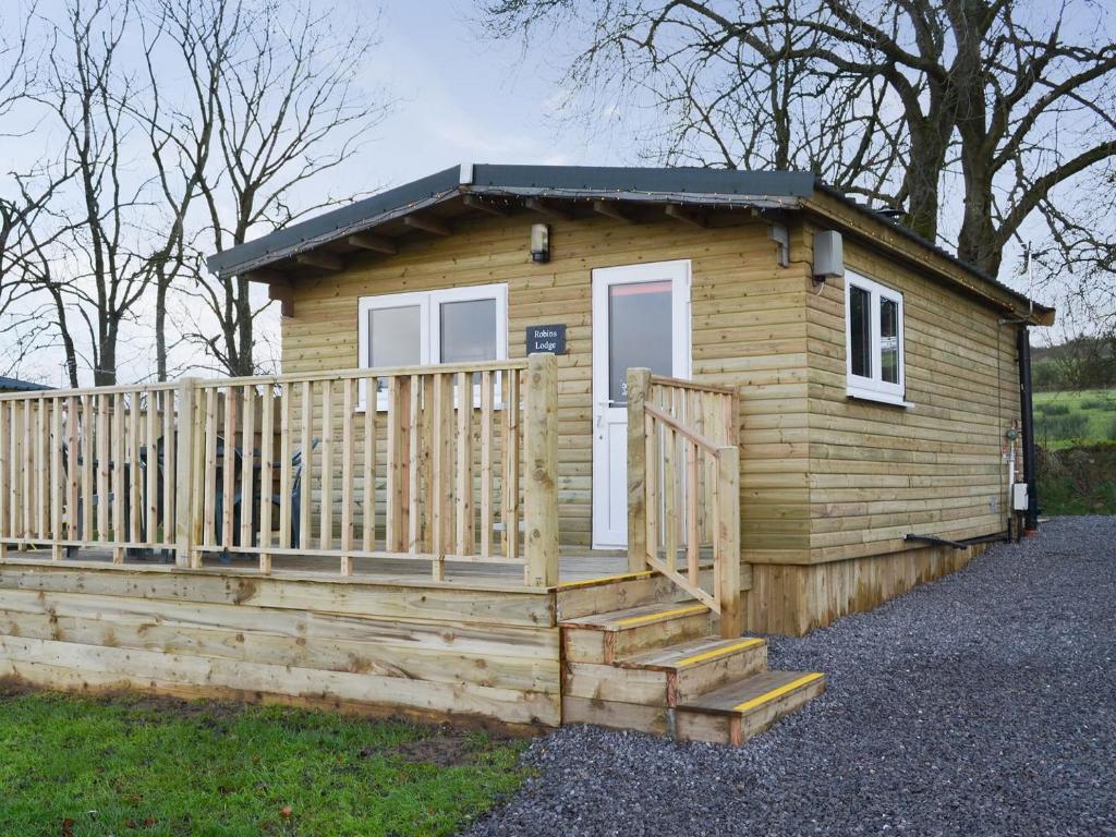 una pequeña casa de madera con una valla de madera en Robins Lodge en Westward