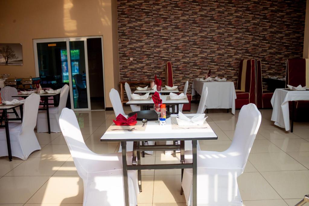 un comedor con mesas blancas y sillas blancas en Top Lodge in Blantyre, en Blantyre