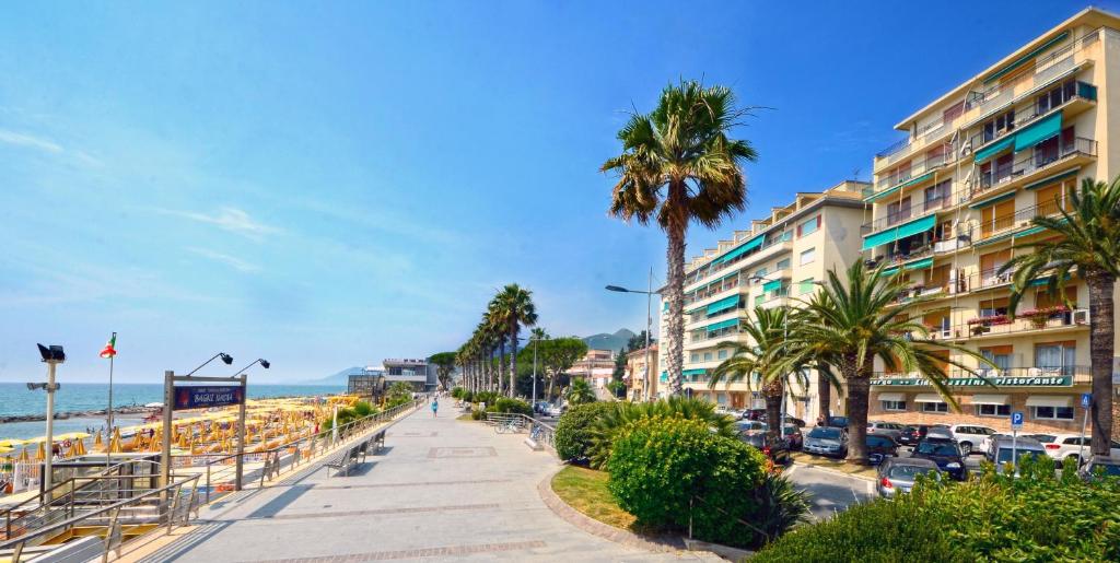 une rue à côté d'une plage bordée de palmiers et d'un bâtiment dans l'établissement Hotel Lido Mazzini, à Loano