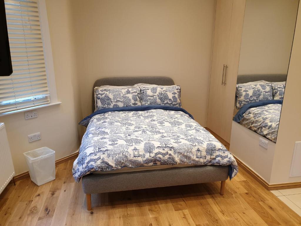 a bedroom with a bed with a blue and white comforter at London Luxury Studio Flat 4 min to Ilford Station with FREE parking FREE WiFi in Ilford