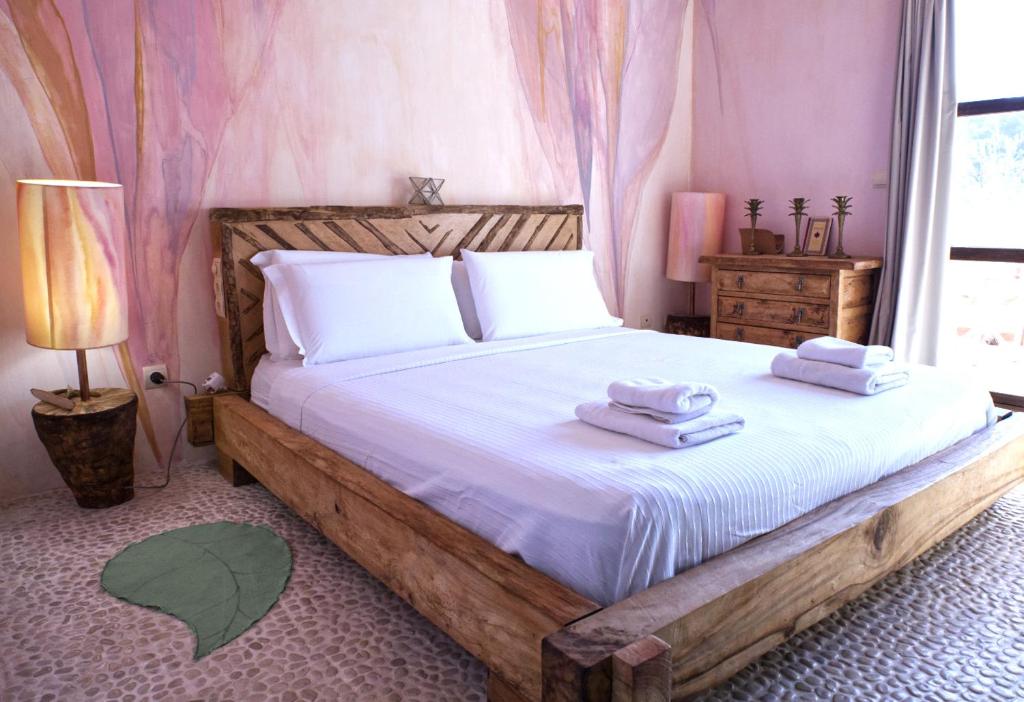 1 dormitorio con cama de madera y toallas en Boutique Hostal La Curandera de Salinas, en Ibiza