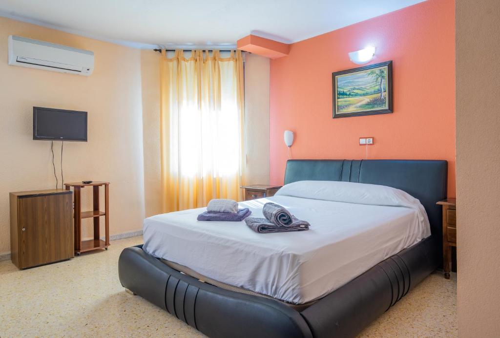 a bedroom with a large bed with orange walls at Hotel Velis - Avenida I in Vélez-Málaga