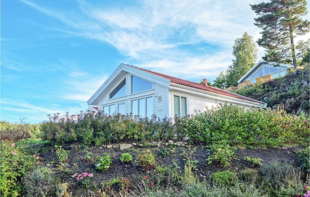 una pequeña casa blanca en una colina con flores en Cozy Home In Tvedestrand With House Sea View en Tvedestrand