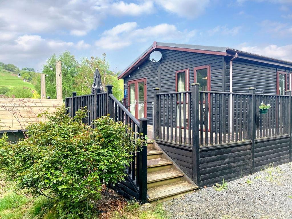 a black house with a staircase leading up to it at Wye Lodge in Aberedw