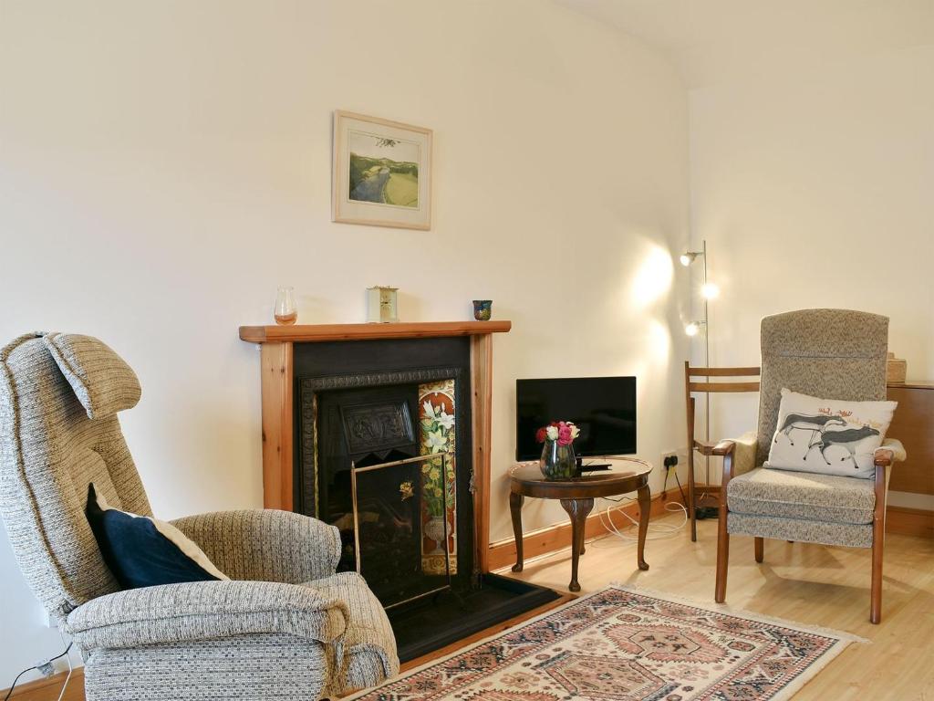 a living room with two chairs and a fireplace at Spey Cottage in Aberlour