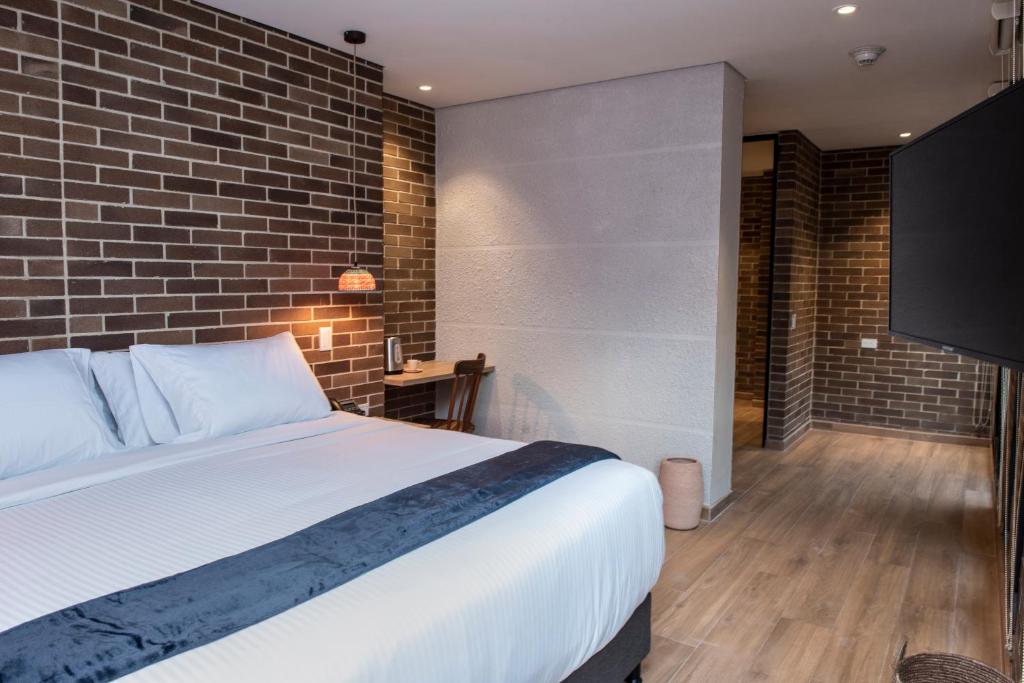 a bedroom with a bed and a brick wall at Casa Rosé Hotel in Carmen de Viboral