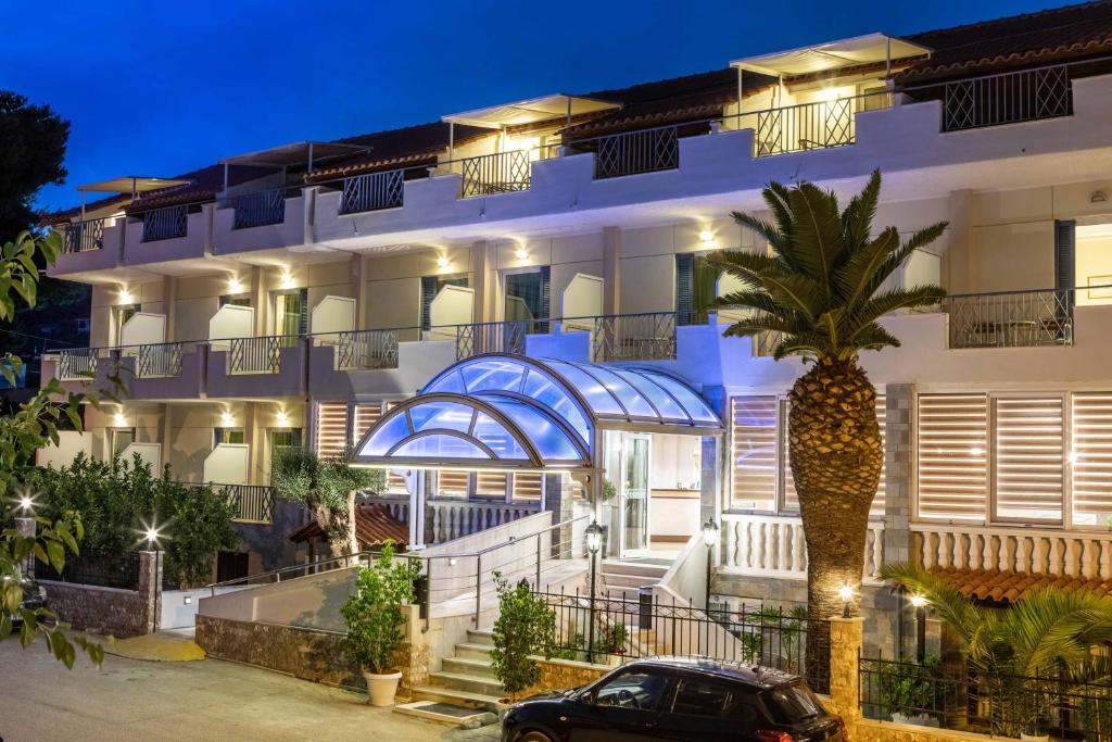 托隆的住宿－Hotel Serenity Tolo，前面有棕榈树的建筑