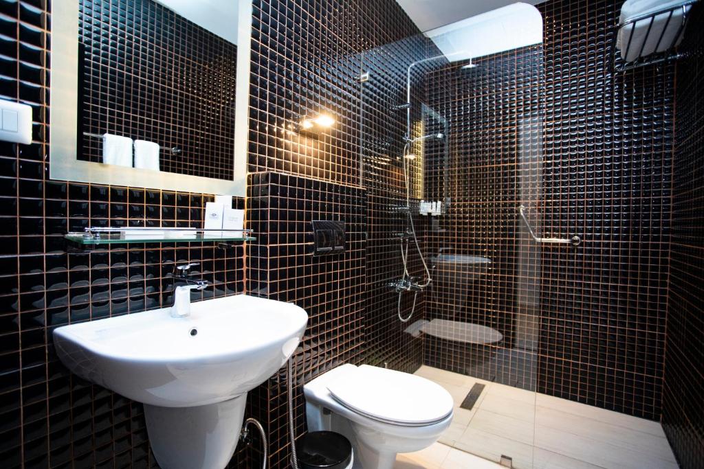 a black tiled bathroom with a sink and a toilet at Hotel Philosophy in Amman