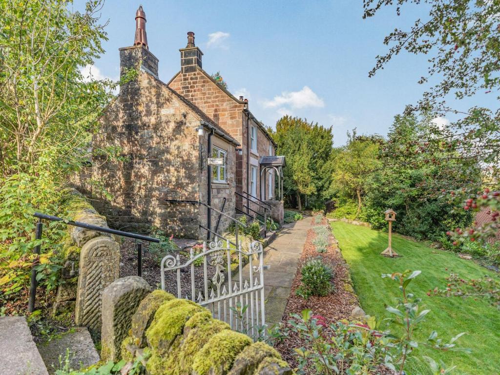 an old stone house with a gate in a garden at Spring Cottage in Endon