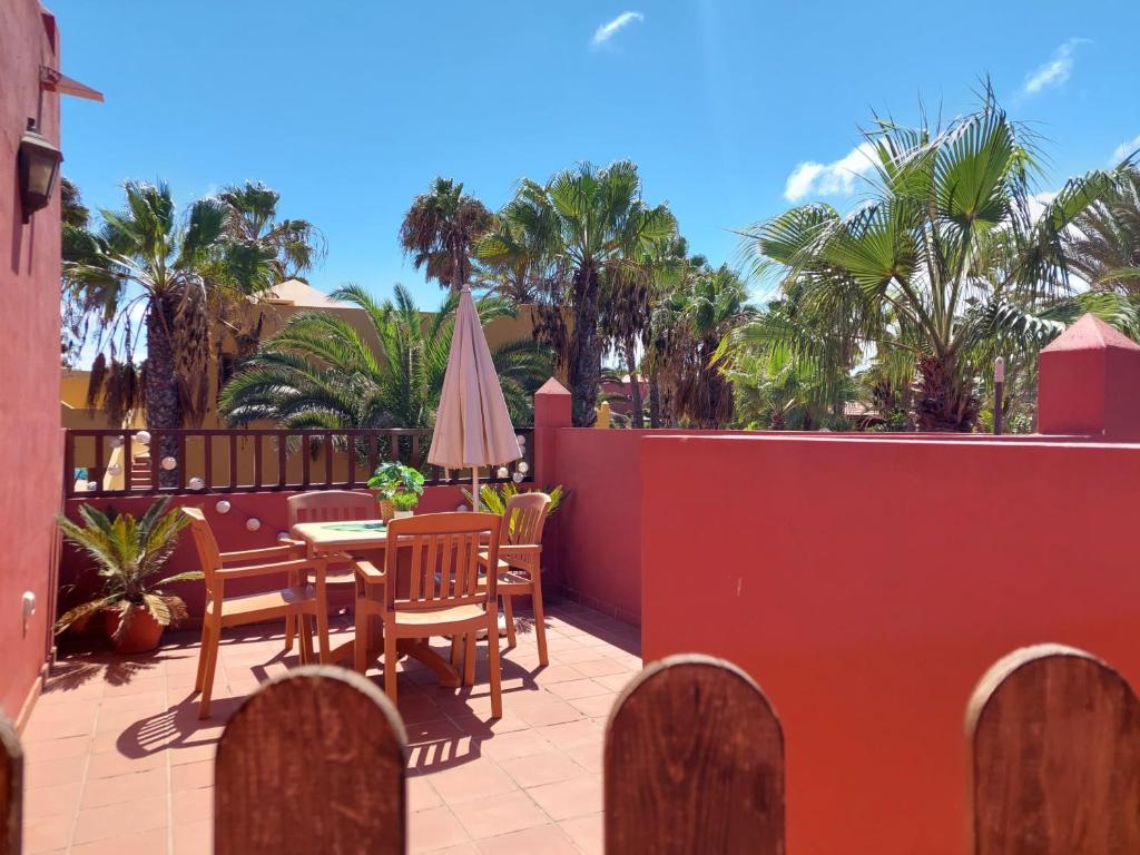 a patio with a table and chairs and palm trees at Sweet Home by Sea You There Fuerteventura in Corralejo