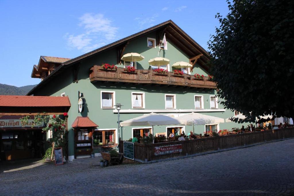 un gran edificio verde con gente sentada fuera de él en Bayerische Gastwirtschaft Dimpfl-Stadl, en Lam