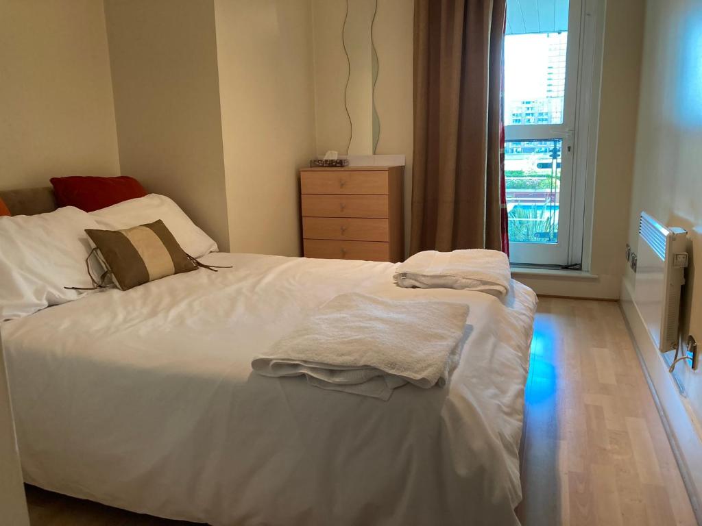 een slaapkamer met een wit bed, een dressoir en een raam bij St George Wharf Apartment in Londen