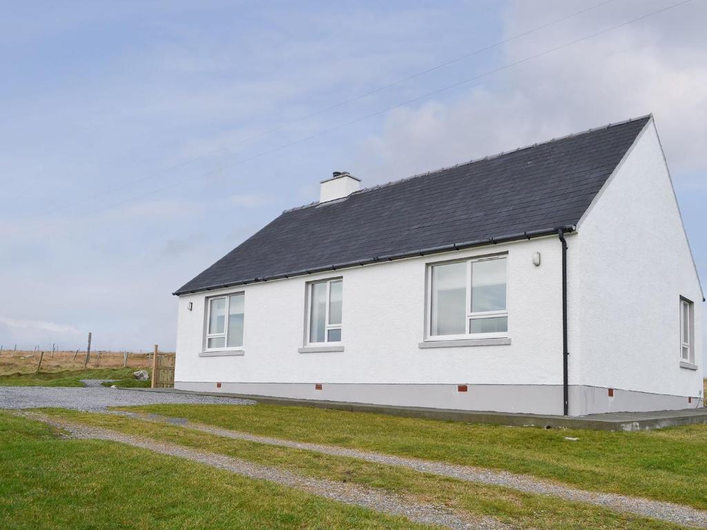 een wit huis met een zwart dak bij West Kilbride in Pollachar