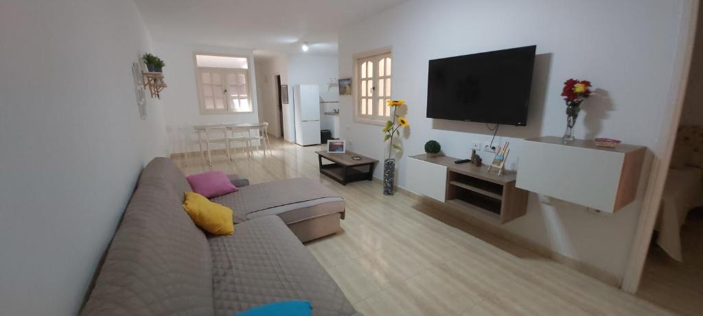 een woonkamer met een bank en een flatscreen-tv bij LA CASITA VECINDARIO in Vecindario