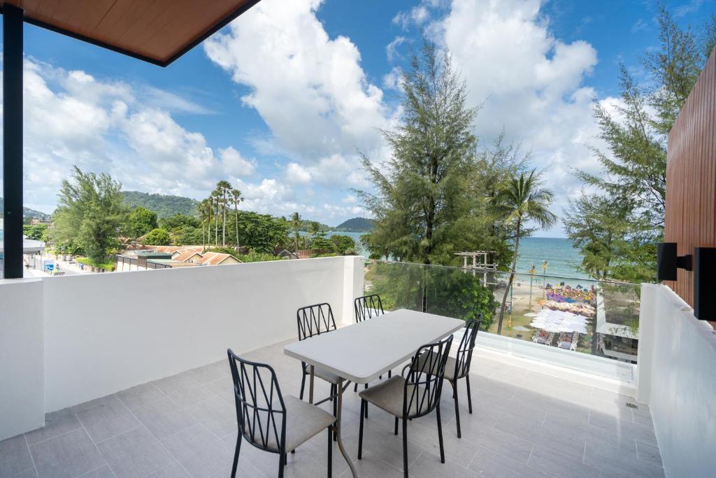 a table and chairs on a balcony with a view of the ocean at By The Beach Home in Patong in Patong Beach