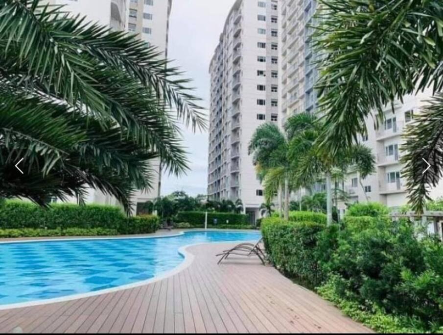 een zwembad met palmbomen en gebouwen bij Comfy Studio unit with Wi-fi, Las Piňas City, parking rent optional in Manilla