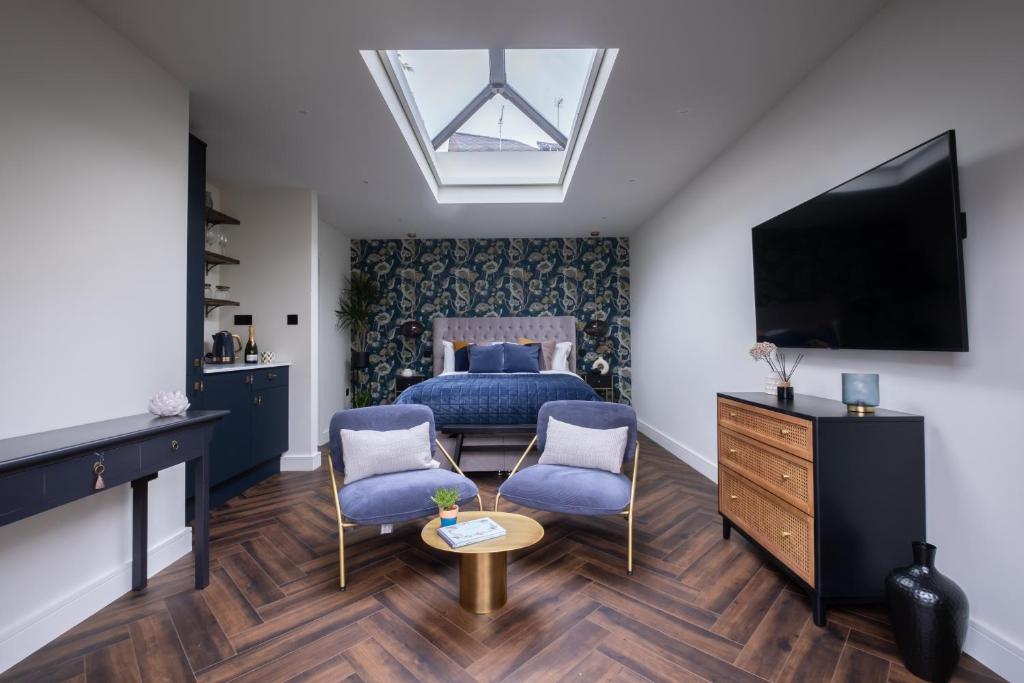 um quarto com uma cama e duas cadeiras e uma televisão em Honeysuckle Lodge em Knaresborough
