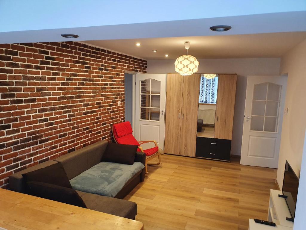 uma sala de estar com um sofá e uma parede de tijolos em RZA Apartment em Bistrita