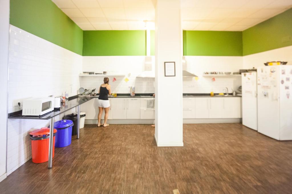 una mujer preparando comida en una cocina con paredes verdes en 360 Hostel Centro, en Barcelona