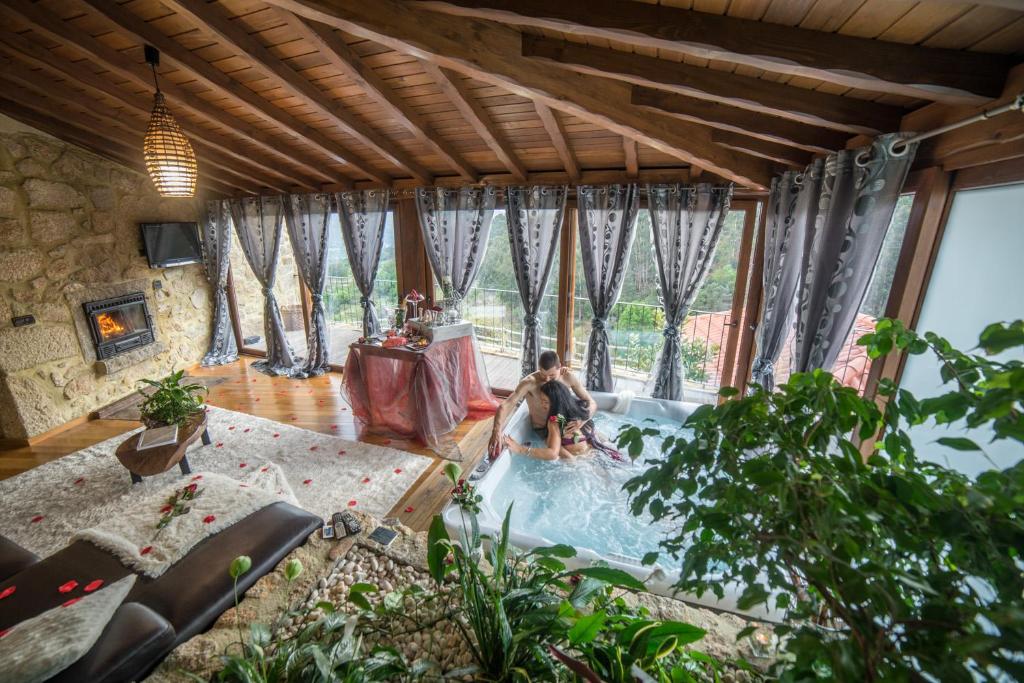 Ein Mann und eine Frau in einem Whirlpool im Wohnzimmer in der Unterkunft Casa Favo de Mel - Jacuzzi Privado in Arcos de Valdevez