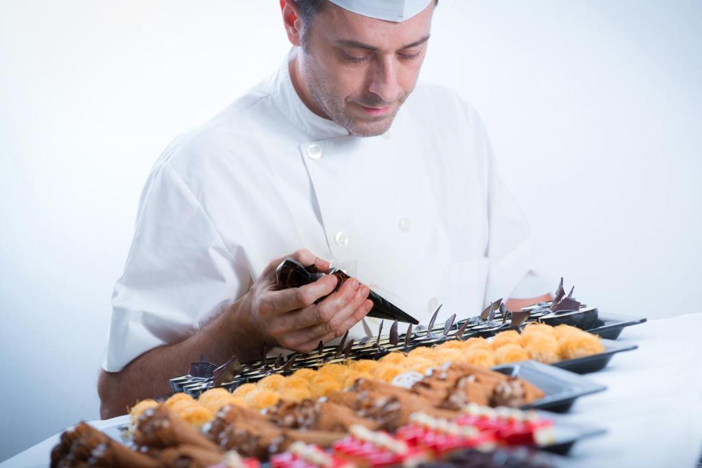 a chef is looking at a tray of food at Hersonissos Maris in Hersonissos
