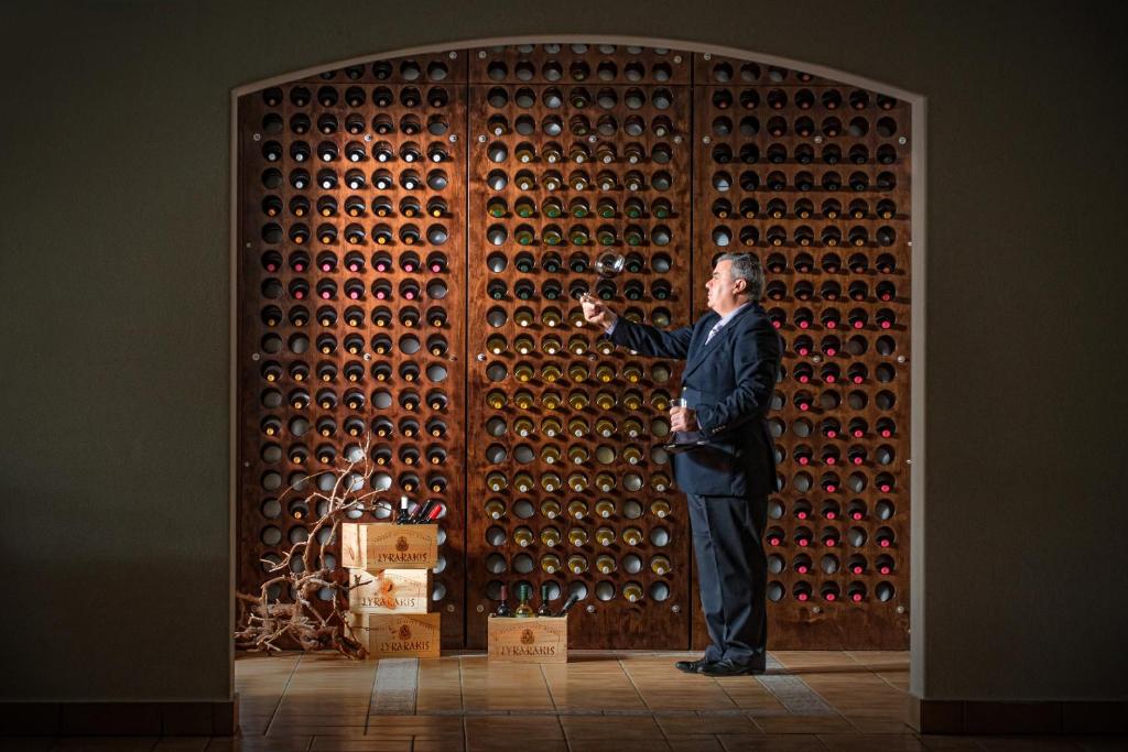 a man standing in front of a wall of wine bottles at Hersonissos Maris in Hersonissos