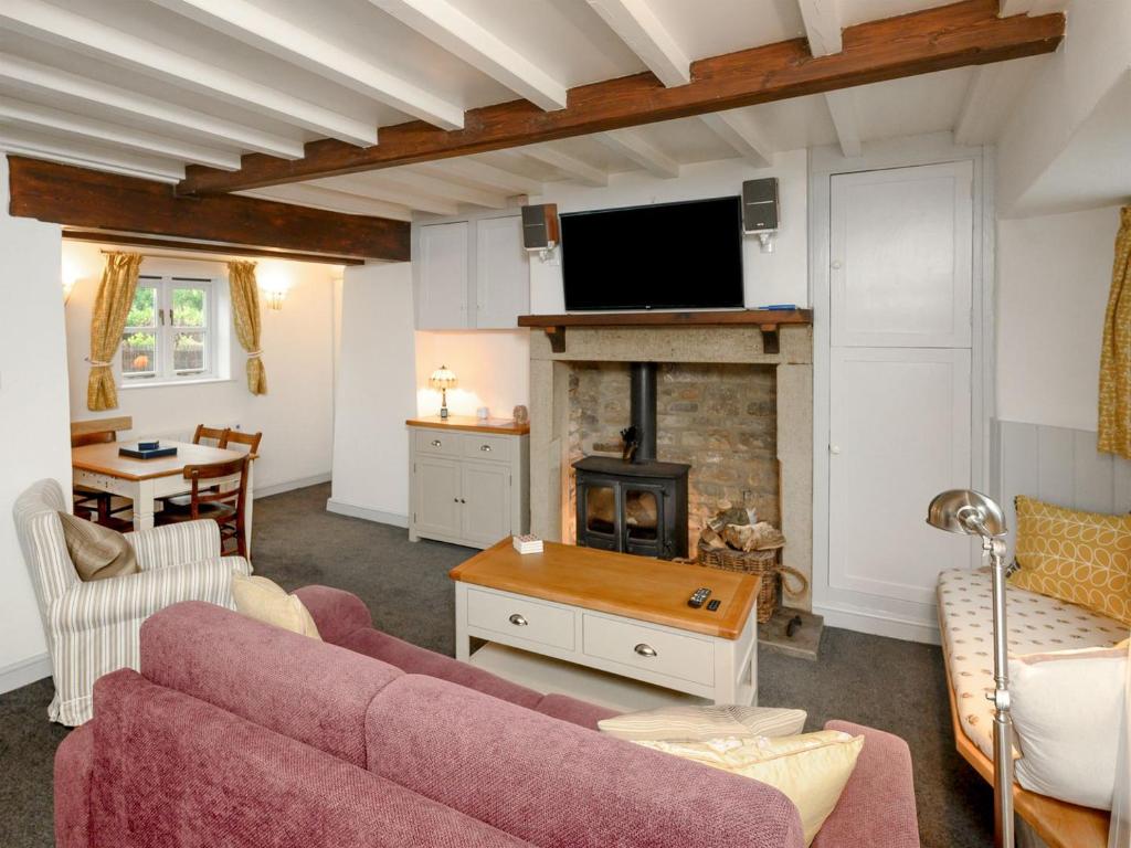 a living room with a couch and a fireplace at Holly Cottage in Kettlewell