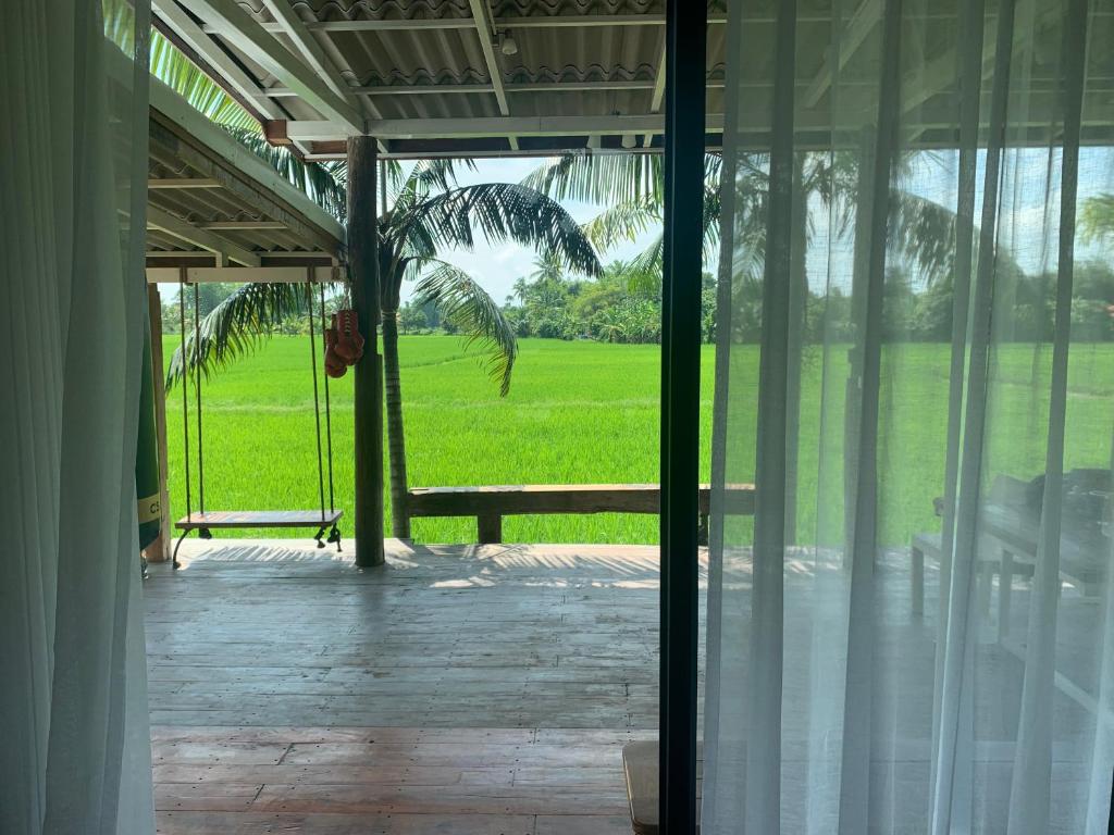une porte ouverte menant à une terrasse couverte avec un palmier dans l'établissement บ้านวิวนา Baan View Na, à Ban Mae Cho
