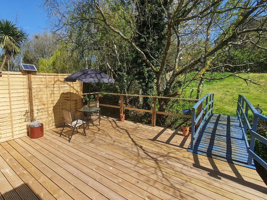 eine Holzterrasse mit einem Tisch und einem Sonnenschirm in der Unterkunft Burnside in Torthorwald