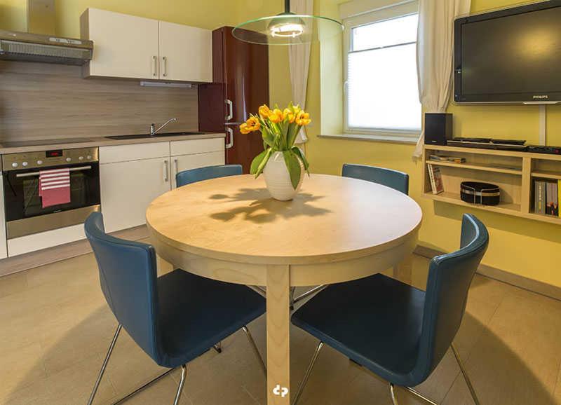 オストゼーバート・ディアーハーゲンにあるSTRANDPERLE App Nr 01 max 4 Persのキッチン(テーブル、椅子、花瓶付)