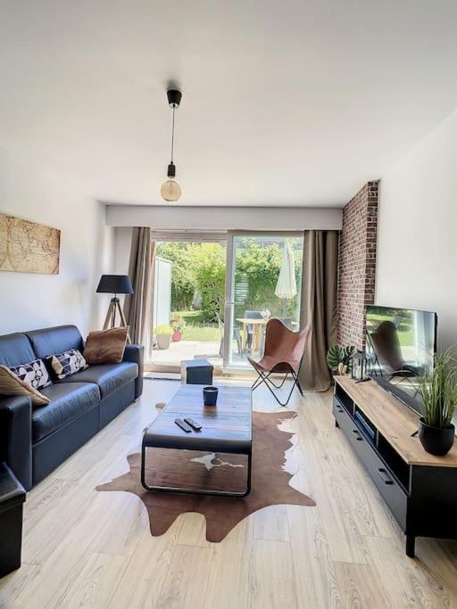 a living room with a blue couch and a table at GRAND APPART TERRASSE PARKING DESIGN in Amiens