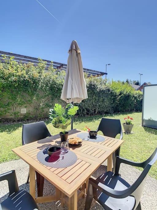 a wooden table with an umbrella and a table and chairs at GRAND APPART TERRASSE PARKING DESIGN in Amiens