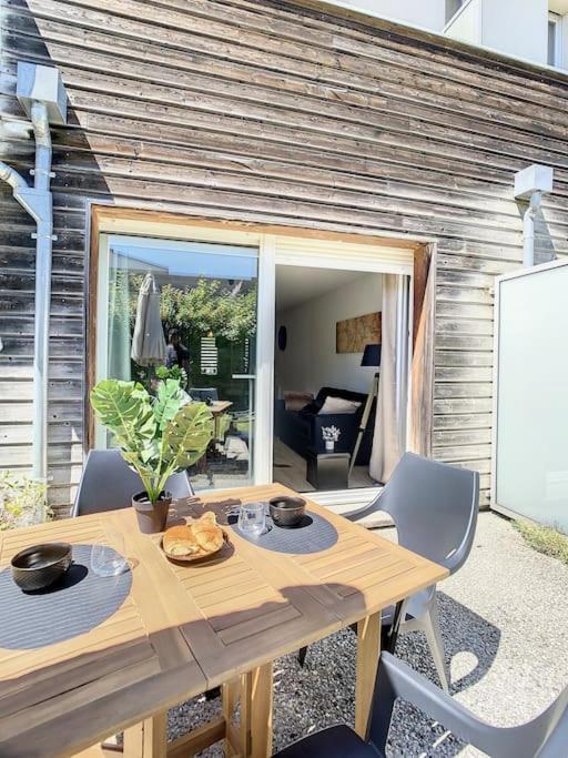 a wooden table and chairs in front of a house at GRAND APPART TERRASSE PARKING DESIGN in Amiens