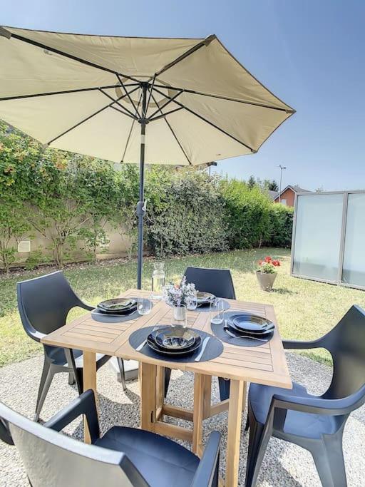 a wooden table with chairs and an umbrella at GRAND APPART TERRASSE PARKING DESIGN in Amiens