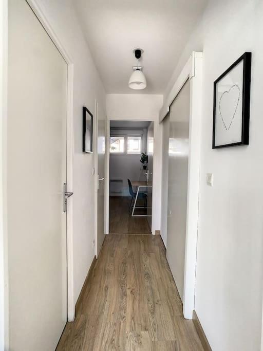 a hallway with white walls and a wooden floor at GRAND APPART TERRASSE PARKING DESIGN in Amiens