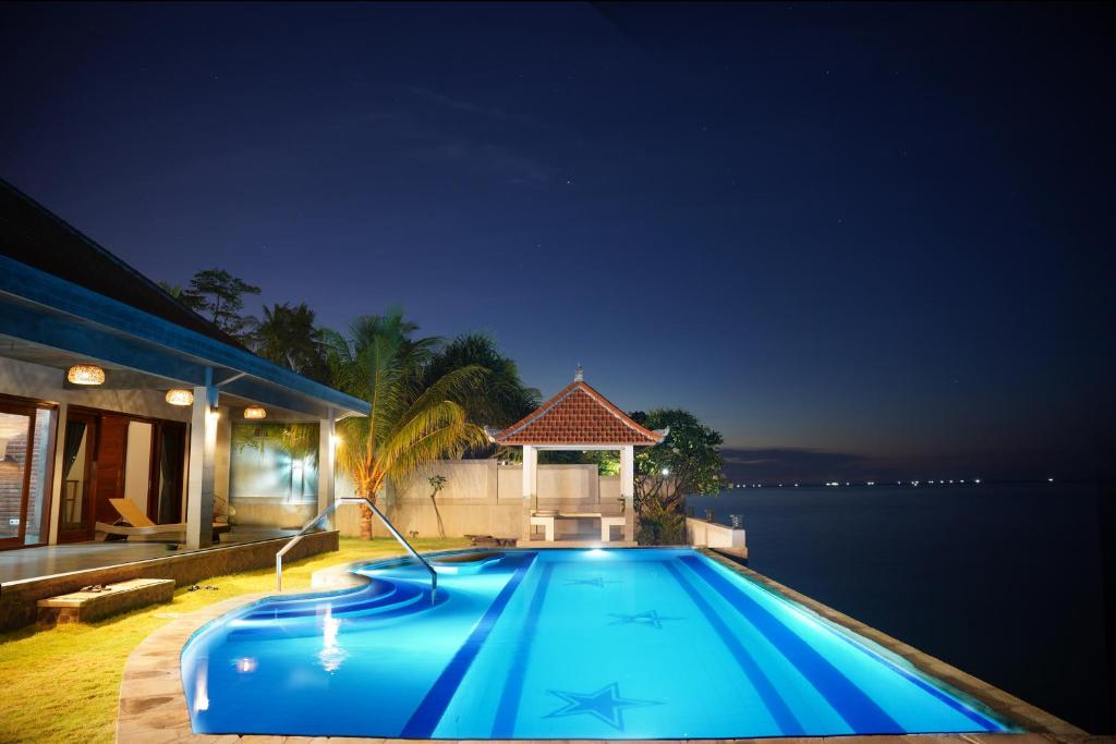 a large blue swimming pool in front of a house at Coco Blu Villa in Singaraja