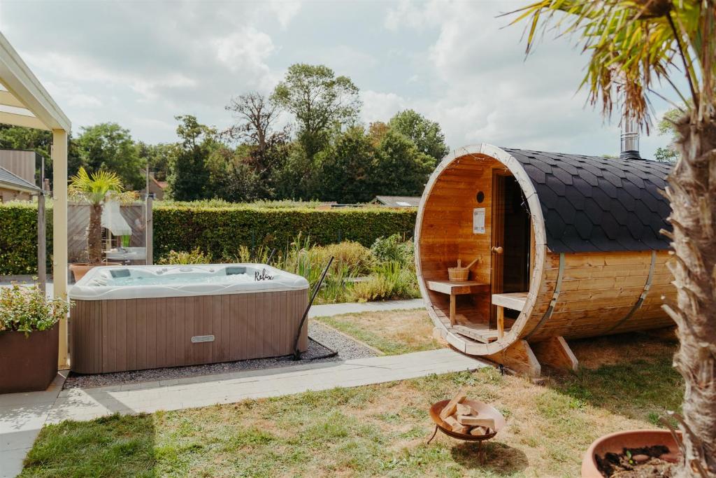 una vasca circolare in legno in un cortile con una casa di Villa Fortem męt sauna en jacuzzi ad Alveringem